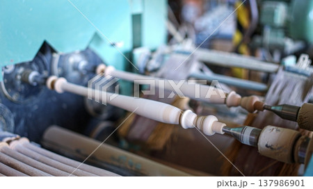 Wooden spindles being shaped on a woodworking lathe machine Wooden spindles being shaped on a woodworking lathe machine 137986901