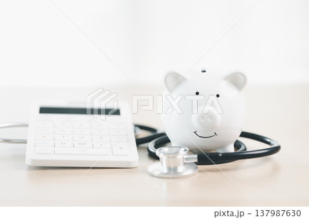 White piggy bank with stethoscope on clean bright background, representing healthcare savings, medical insurance, budgeting and financial planning for hospital bills and wellness costs. healthcare White piggy bank with stethoscope on clean bright background, representing healthcare savings, medical insurance, budgeting and financial planning for hospital bills and wellness costs. healthcare 137987630