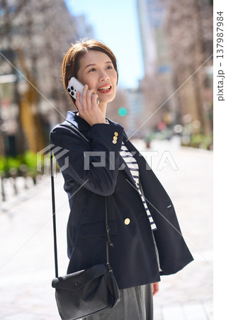 街を歩きながらスマートフォンで通話する30代日本人ビジネスウーマン 137987984