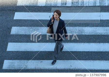 街を歩きながらスマートフォンで通話する30代日本人ビジネスウーマン 137987996