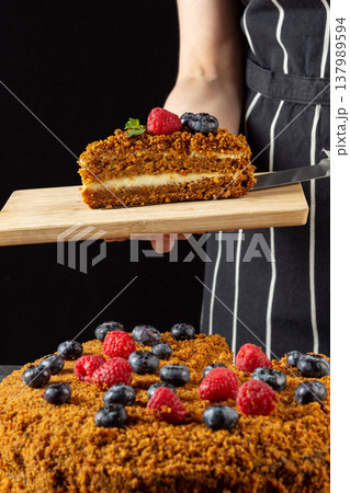 A female chef bakes and eats a piece of homemade carrot cake on a dark background A female chef bakes and eats a piece of homemade carrot cake on a dark background 137989594