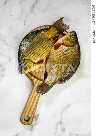 The fish are golden with distinct scales and fins, ready for cooking 137989854