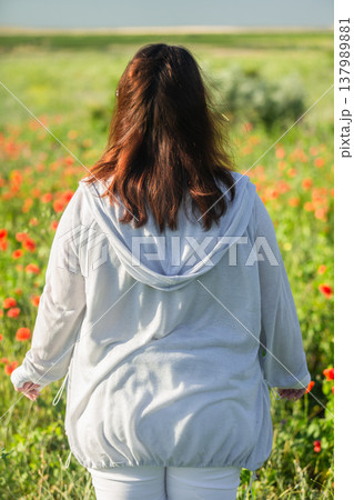 Portrait of a happy young woman with her back against a backdrop of wildflowers. Body positivity 137989881