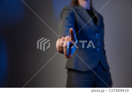 A portrait of a faceless woman in a business suit, holding her hand forward with her index finger raised. A warning gesture. Blue color correction 137989919