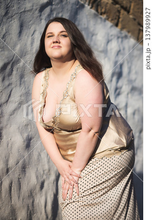 Portrait of a happy young woman against a wall. Body positivity. Vertical photo Portrait of a happy young woman against a wall. Body positivity. Vertical photo 137989927