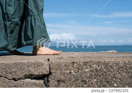 海沿いの堤防を裸足で歩く女性の足元 137992101