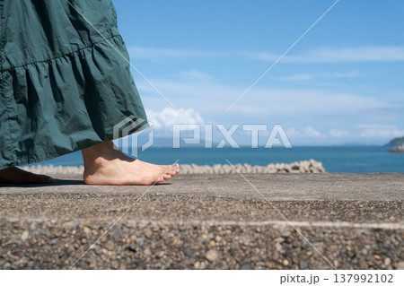 海沿いの堤防を裸足で歩く女性の足元 137992102