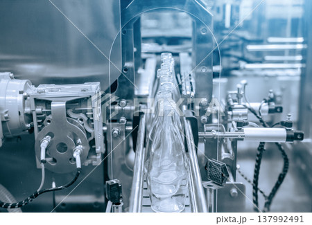 The hi-technology of drinking water manufacturing process. The empty drinking water bottles on the conveyor belt for filling process. The hi-technology of drinking water manufacturing process. The empty drinking water bottles on the conveyor belt for filling process. 137992491