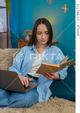 Young woman studying online with laptop and book making notes seriously focused distance education 137992772