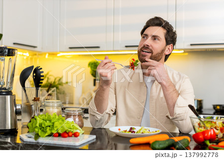 Middle-aged man enjoying fresh vegetable salad meal in home kitchen for healthy diet daily nutrition 137992778