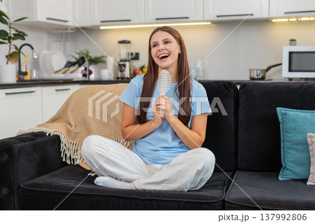 Young woman sings into hair comb like microphone dances to favorite song star fantasy playful mood Young woman sings into hair comb like microphone dances to favorite song star fantasy playful mood 137992806