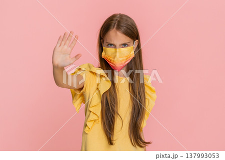 Child girl kid wearing protective mask showing stop hand sign then smiling with relief after removal Child girl kid wearing protective mask showing stop hand sign then smiling with relief after removal 137993053