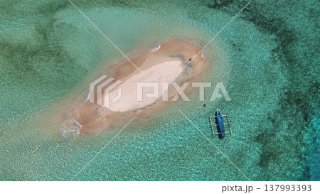 Aerial pristine white sandbar surrounded by crystal turquoise water with a traditional outrigger boat moored nearby, tranquil, secluded tropical travel and paradise serenity. East Gili Islands, Lombok Aerial pristine white sandbar surrounded by crystal turquoise water with a traditional outrigger boat moored nearby, tranquil, secluded tropical travel and paradise serenity. East Gili Islands, Lombok 137993393