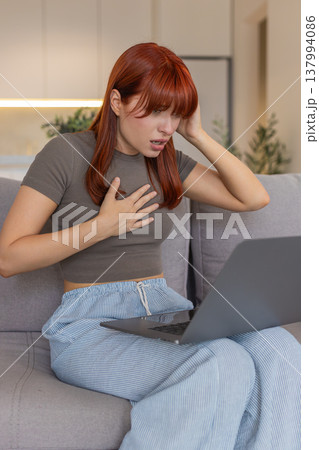 Young woman with laptop sad look game defeat or project rejection nervous clicks failed bet bad news 137994086