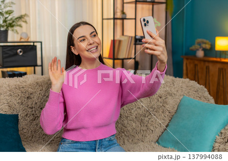 Young woman on sofa having video call laughing and using expressive hand gestures with real emotion Young woman on sofa having video call laughing and using expressive hand gestures with real emotion 137994088