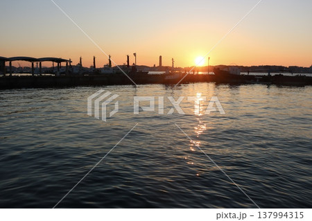 港に沈む夕日と水面に映る光の反射が美しいサンセット風景 港に沈む夕日と水面に映る光の反射が美しいサンセット風景 137994315