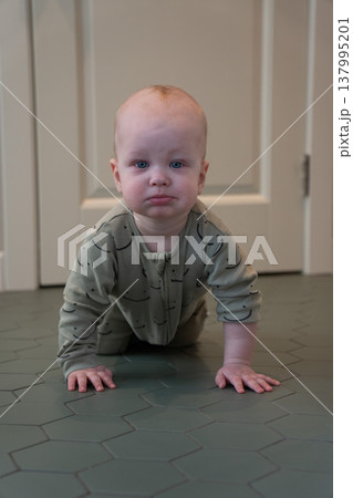 Baby crawls on floor in home interior with soft light and minimal setting, early development stage and exploration in everyday domestic environment. Child development, parenting content, family 137995201