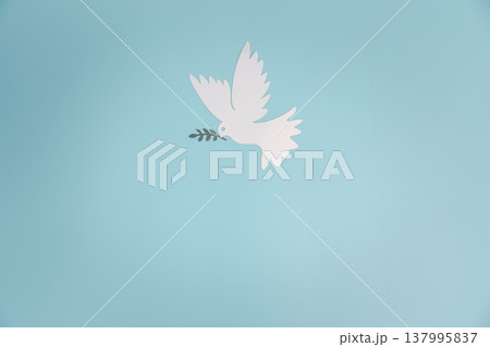 Minimal paper-cut white dove carrying an olive branch flying in soft blue sky with clouds and subtle peace sign, copy space for message, symbol of harmony, hope and unity, ideal for Peace Day. Minimal paper-cut white dove carrying an olive branch flying in soft blue sky with clouds and subtle peace sign, copy space for message, symbol of harmony, hope and unity, ideal for Peace Day. 137995837