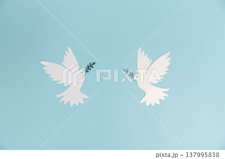 Two paper-cut white doves with olive branches facing each other on soft blue background with copy space, minimalist symbol of peace, harmony, unity for posters, banners and greetings. peace, harmony 137995838