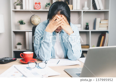 Stressed office worker covering face with hands at desk, overwhelmed by paperwork and laptop, financial anxiety, burnout, deadline pressure, mental health and work life balance concept. stressed 137995952