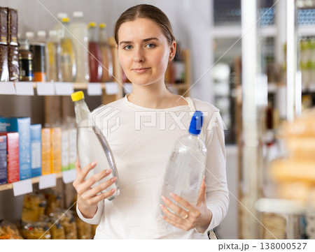 Girl customer in supermarket examines soda bottle, chooses food-stuff in grocery Girl customer in supermarket examines soda bottle, chooses food-stuff in grocery 138000527