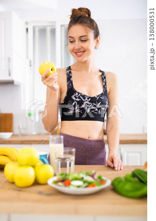 Young sportive woman eating apple in kitchen Young sportive woman eating apple in kitchen 138000531
