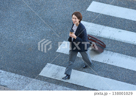 スーツケースを持って街を移動する30代日本人ビジネスウーマン 138001029