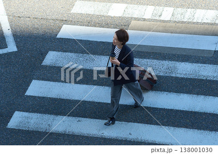スーツケースを持って街を移動する30代日本人ビジネスウーマン スーツケースを持って街を移動する30代日本人ビジネスウーマン 138001030