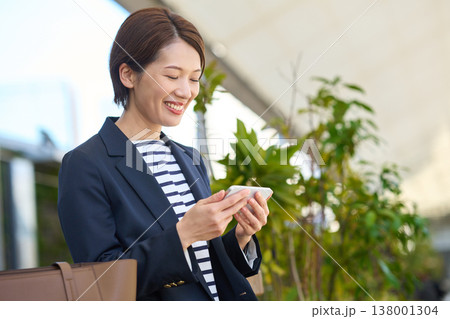 スマートフォンを見て喜ぶ30代日本人ビジネスウーマン スマートフォンを見て喜ぶ30代日本人ビジネスウーマン 138001304