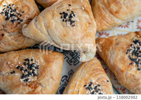 Samsa made from puff pastry dough. A triangular pie with meat filling with sesame seeds food top view 138002982