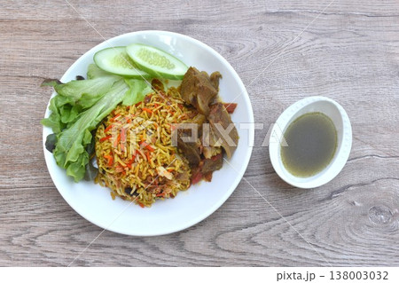 biryani rice cooked with braised beef meat stew in curry and fresh vegetable salad on plate dipping spicy chili sauce 138003032