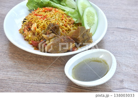 biryani rice cooked with braised beef meat stew in curry and fresh vegetable salad on plate dipping spicy chili sauce 138003033