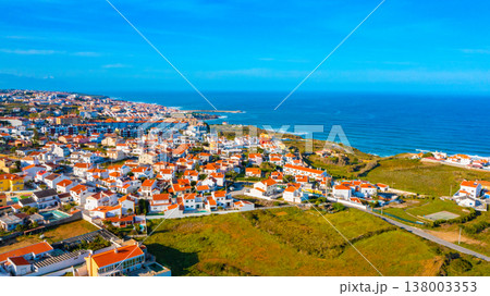 Drone view of a beautiful European city with a hilly landscape on ocean background. Aerial view of a small European town against blue sky and Atlantic Ocean.  Beautiful natural landscape. Portugal. 138003353