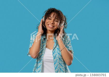 African Pretty Woman Listening Music, Dances With Wireless Headphones On Blue African Pretty Woman Listening Music, Dances With Wireless Headphones On Blue 138003701