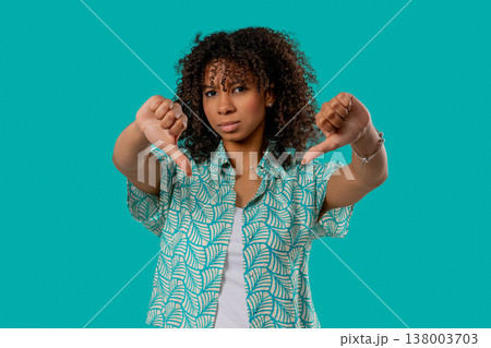 African Teen Girl With Dislike Sign. Stylish Lady Showing Thumbs-Down on blue 138003703