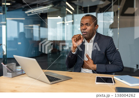 Entrepreneur experiencing discomfort and pain in his chest, coughing while working in a modern office environment, feeling sick and needing medical attention 138004262