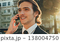 Smiling businessman in the city talking on a cell phone. Portrait Businessman in a business suit in the the street a with mobile phone. Young man in a business  suit talking on a smartphone. 138004750