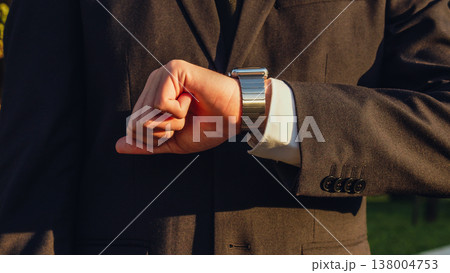 Businessman looks at the smartwatch on his hand. Businessman is checking time on the smartwatch. Close up. Modern gadgets and people concept. Modern communication. 138004753