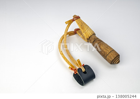 Antique Rustic Handmade Wooden Slingshot with Stretched Yellow Latex Rubber Bands and Black Leather Ammunition Pouch Isolated on Clean White Studio Background 138005244
