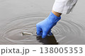A close-up of a hand in a blue glove collecting river water with using a test tube 138005353