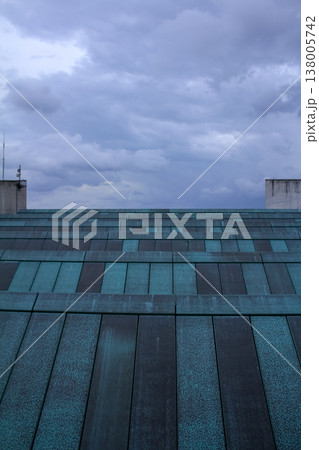 Close-up view of the rooftop of building with the blue sky and clouds. Building exterior. Close-up view of the rooftop of building with the blue sky and clouds. Building exterior. 138005742