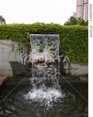 Close-up view of a cascading feature water fountain in a public park. Powerful spout of cascading water pours into the pool. Close-up view of a cascading feature water fountain in a public park. Powerful spout of cascading water pours into the pool. 138005908