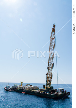 透き通った青い海と海面に浮かぶ工事のための大型クレーン船　地中海に浮かぶフランス領のコルシカ島にて 138007490