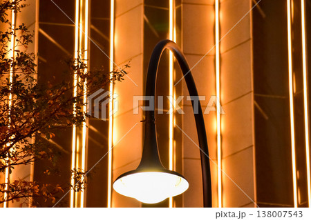 Close-up of the street light at night with buildings in the background. Cityscape and street scene at night with dark background. Close-up of the street light at night with buildings in the background. Cityscape and street scene at night with dark background. 138007543