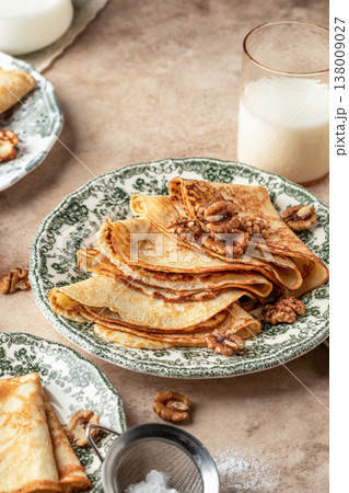 Delicious crepes served with nuts folded on ceramic plate. Tasty morning breakfast on beige table background, Maslenitsa concept 138009027