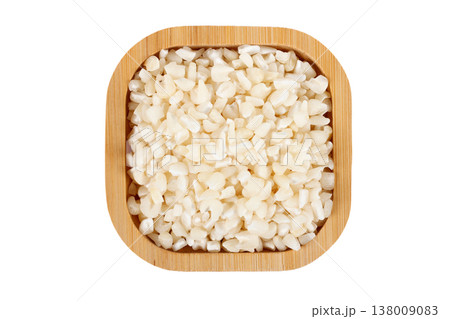 Raw dried white corn, used in the preparation of canjica, a Brazilian dessert made with corn, in a wooden bowl, isolated on a white background. Raw dried white corn, used in the preparation of canjica, a Brazilian dessert made with corn, in a wooden bowl, isolated on a white background. 138009083
