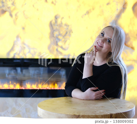 Cozy glamour mature woman leaning on table near fireplace black dress indoor fashion lifestyle confident pose elegant atmosphere Cozy glamour mature woman leaning on table near fireplace black dress indoor fashion lifestyle confident pose elegant atmosphere 138009302
