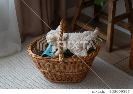 Wicker basket with plush toy and items stands on carpet in home interior with soft natural light and cozy setting, decorative storage element in domestic space. Home decor, storage concept, lifestyle Wicker basket with plush toy and items stands on carpet in home interior with soft natural light and cozy setting, decorative storage element in domestic space. Home decor, storage concept, lifestyle 138009597
