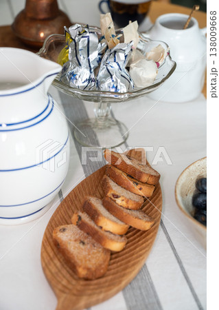 Table with rusks with sugar, blueberries, candies and water pitcher in home kitchen with natural light, everyday meal arrangement in domestic setting. Food styling, breakfast content, table setting 138009668