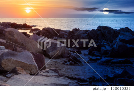 sea with rocky shore. day meet night. sun and moon over beautiful autumn equinox scenery and vacation concept on the rocky beach at twilight. scenic destination of seaside near old resort town 138010325